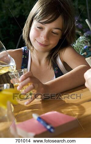 A young girl pouring herself a glass of juice, outdoors View Large Photo Image Picture - A young girl pouring herself a glass of juice, outdoors. Fotosearch