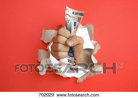 A fist breaking through a wall holding Euro banknotes View Large Photo Image Stock Photo - A fist breaking through a wall holding Euro banknotes. Fotosearch