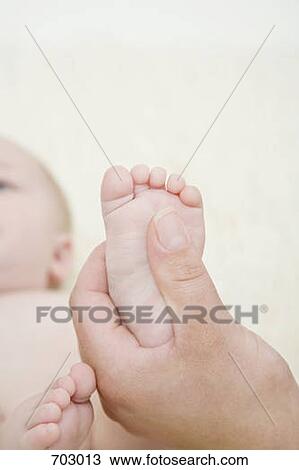 A human hand holding a baby's foot View Large Photo Image Stock Image - A human hand holding a baby's foot. Fotosearch