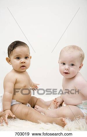 Two babies sitting face to face, looking at camera View Large Photo Image Stock Photo - Two babies sitting face to face, looking at camera. Fotosearch