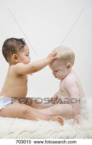Stock Photography - Two babies sitting face to face. Fotosearch