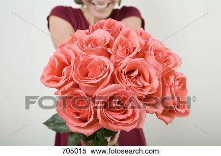 Stock Photography - A Latin American woman presenting a bouquet of roses. Fotosearch