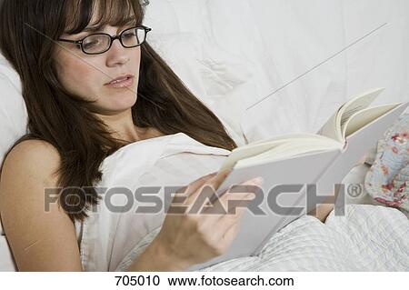 A Latin American woman reading a book in bed View Large Photo Image Stock Image - A Latin American woman reading a book in bed. Fotosearch