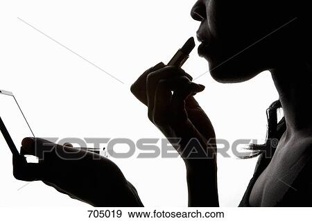 Stock Photo - An African American woman applying lipstick, silhouette. Fotosearch