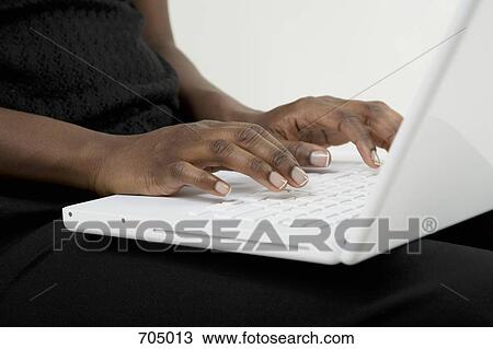 Stock Image - An African American woman typing on a laptop. Fotosearch