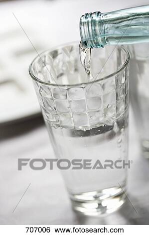 Bottled water pouring into a glass View Large Photo Image Stock Photograph - Bottled water pouring into a glass. Fotosearch