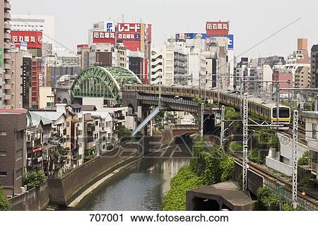 Stock Image - Train crossing the Kanda River with Akihabara district in background, Tokyo. Fotosearch