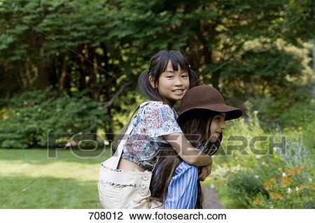 Stock Image - A girl giving another girl a piggyback ride. Fotosearch