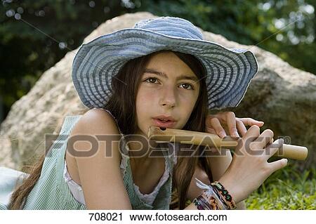 Stock Image - A girl lying down playing a flute. Fotosearch