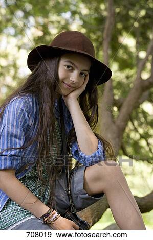 A girl sitting on a tree branch, portrait View Large Photo Image Stock Photo - A girl sitting on a tree branch, portrait. Fotosearch