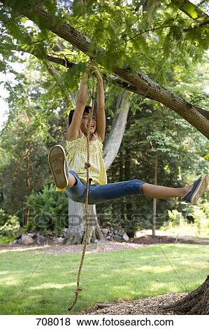 Stock Photo - A girl swinging on a rope swing. Fotosearch