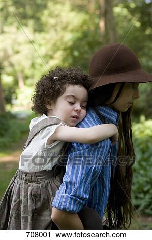 Stock Image - A pre-adolescent girl carrying a young girl on her back. Fotosearch
