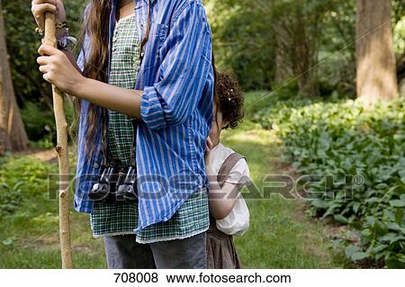 Stock Photo - A young girl hiding behind an older girl. Fotosearch