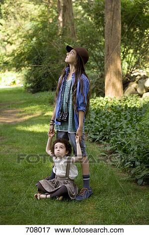 Stock Photo - Two girls in nature looking up. Fotosearch