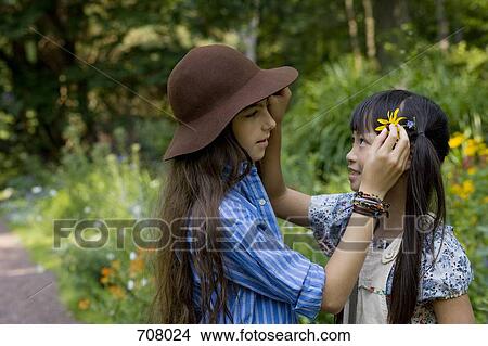 Two girls putting flowers in each other's hair View Large Photo Image Picture - Two girls putting flowers in each other's hair. Fotosearch