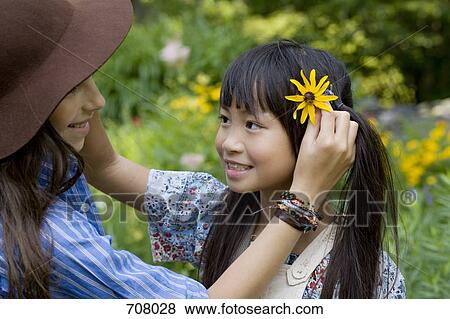 Two girls putting flowers in each other's hair View Large Photo Image Stock Photo - Two girls putting flowers in each other's hair. Fotosearch