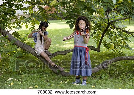 Two young girls playing instruments in nature View Large Photo Image Stock Image - Two young girls playing instruments in nature. Fotosearch