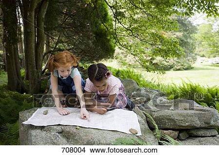 Two young girls reading a map, outdoors View Large Photo Image Picture - Two young girls reading a map, outdoors. Fotosearch