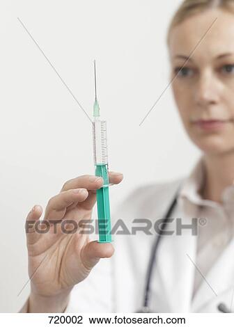 Stock Image - A female doctor preparing a syringe. Fotosearch