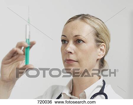 Stock Photograph - A female doctor preparing a syringe. Fotosearch