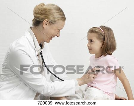 A female pediatrician putting a stethoscope on the heart of a young girl View Large Photo Image Stock Photo - A female pediatrician putting a stethoscope on the heart of a young girl. Fotosearch