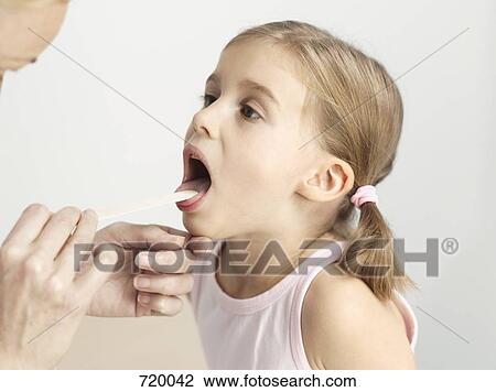 A young girl having her throat examined with a tongue depressor View Large Photo Image Stock Image - A young girl having her throat examined with a tongue depressor. Fotosearch