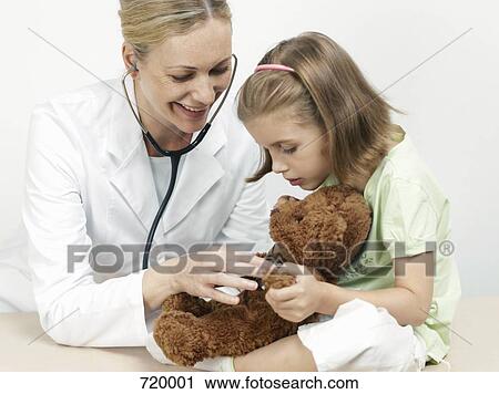 Female pediatrician examining a girl's teddy bear View Large Photo Image Stock Image - Female pediatrician examining a girl's teddy bear . Fotosearch