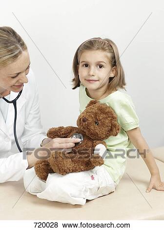 Female pediatrician examining a girl's teddy bear View Large Photo Image Stock Photo - Female pediatrician examining a girl's teddy bear. Fotosearch
