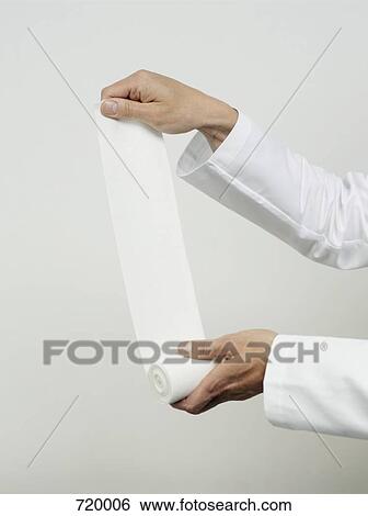 Stock Photograph - Human hands unrolling a strip of gauze. Fotosearch