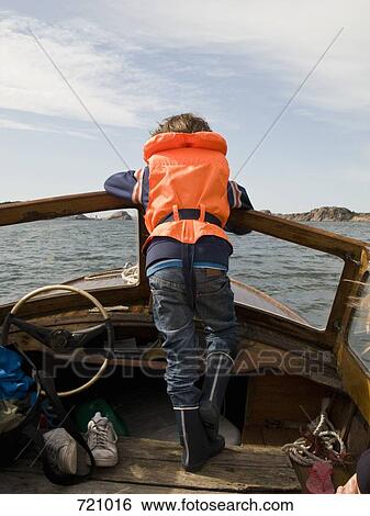 Stock Photograph - A boy riding in a motorboat, rear view. Fotosearch