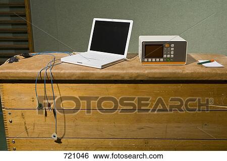 Stock Photograph - A laptop and an old EKG machine on a wooden trunk. Fotosearch