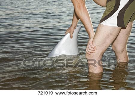 A man standing in the sea holding a fin View Large Photo Image Stock Photo - A man standing in the sea holding a fin . Fotosearch