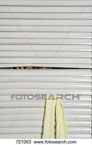 Stock Image - A person peeking through window blinds. Fotosearch