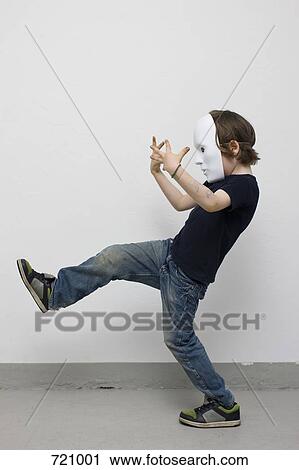 A young boy wearing a mask and standing on one leg, side view View Large Photo Image Stock Image - A young boy wearing a mask and standing on one leg, side view. Fotosearch