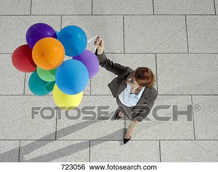 A businesswoman holding a bunch of helium balloons View Large Photo Image Stock Photograph - A businesswoman holding a bunch of helium balloons. Fotosearch