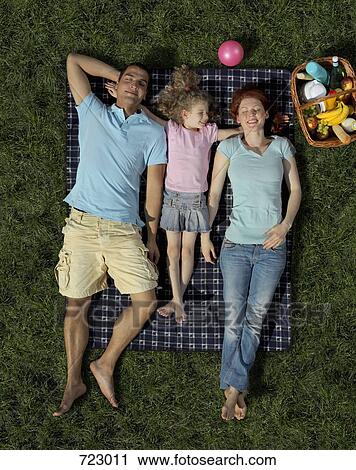 Stock Image - A family lying on a blanket on grass. Fotosearch