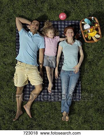 A family lying on a blanket on the grass View Large Photo Image Stock Photo - A family lying on a blanket on the grass. Fotosearch