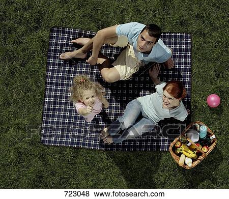 A family sitting on a blanket and having a picnic View Large Photo Image Stock Photo - A family sitting on a blanket and having a picnic. Fotosearch