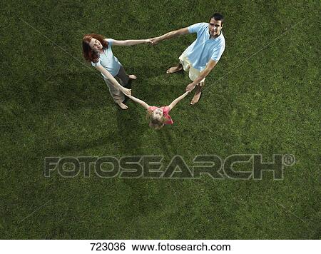 Stock Photograph - A family standing and holding hands in a circle. Fotosearch