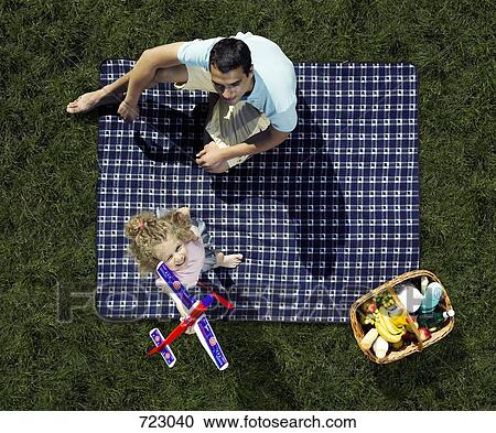 Stock Image - A father and daughter having a picnic and playing with a toy airplane. Fotosearch