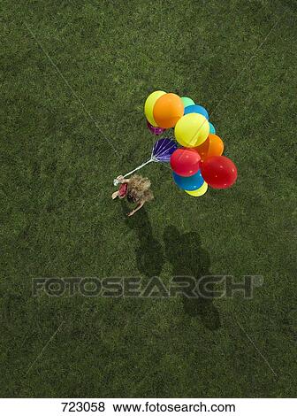 A girl carrying a bunch of helium balloons View Large Photo Image Stock Photo - A girl carrying a bunch of helium balloons. Fotosearch