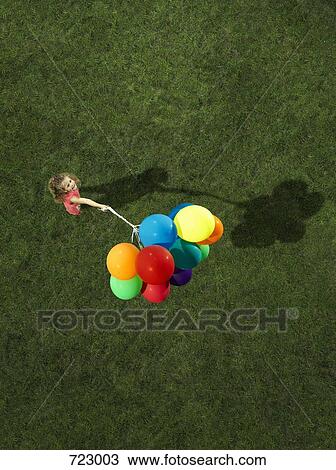 A girl holding a bunch of helium balloons View Large Photo Image Stock Image - A girl holding a bunch of helium balloons. Fotosearch
