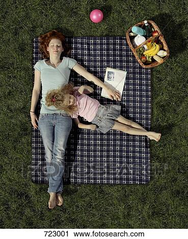 A mother and daughter lying on a blanket on the grass resting View Large Photo Image Stock Image - A mother and daughter lying on a blanket on the grass resting. Fotosearch