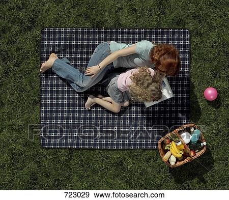 A mother and daughter lying on a blanket on the grass and reading a book View Large Photo Image Stock Photo - A mother and daughter lying on a blanket on the grass and reading a book . Fotosearch
