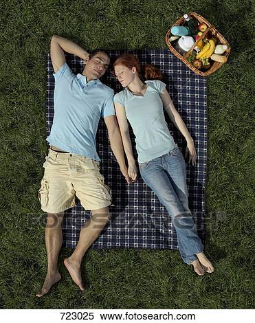 Stock Photography - A young couple sleeping on a blanket in the park. Fotosearch