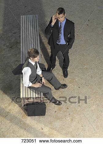 Two businessmen waiting by a bench View Large Photo Image Stock Image - Two businessmen waiting by a bench. Fotosearch
