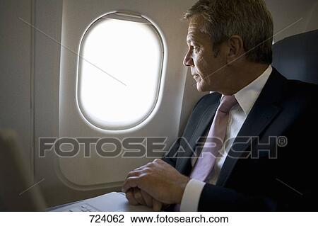 A businessman looking out the window of a plane View Large Photo Image Stock Image - A businessman looking out the window of a plane. Fotosearch