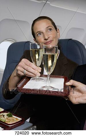 A businesswoman being served champagne on a plane View Large Photo Image Stock Image - A businesswoman being served champagne on a plane. Fotosearch
