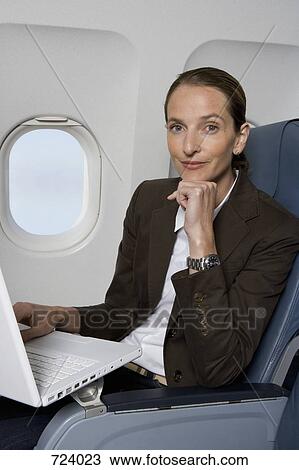 A businesswoman working on a laptop on a plane View Large Photo Image Stock Image - A businesswoman working on a laptop on a plane. Fotosearch