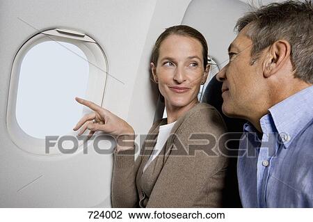 A couple looking out the window of a plane View Large Photo Image Stock Image - A couple looking out the window of a plane. Fotosearch